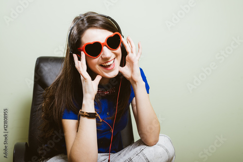 portrait of happy smiling pretty girl holding headphones listening music and looking at camera over olive copy space background