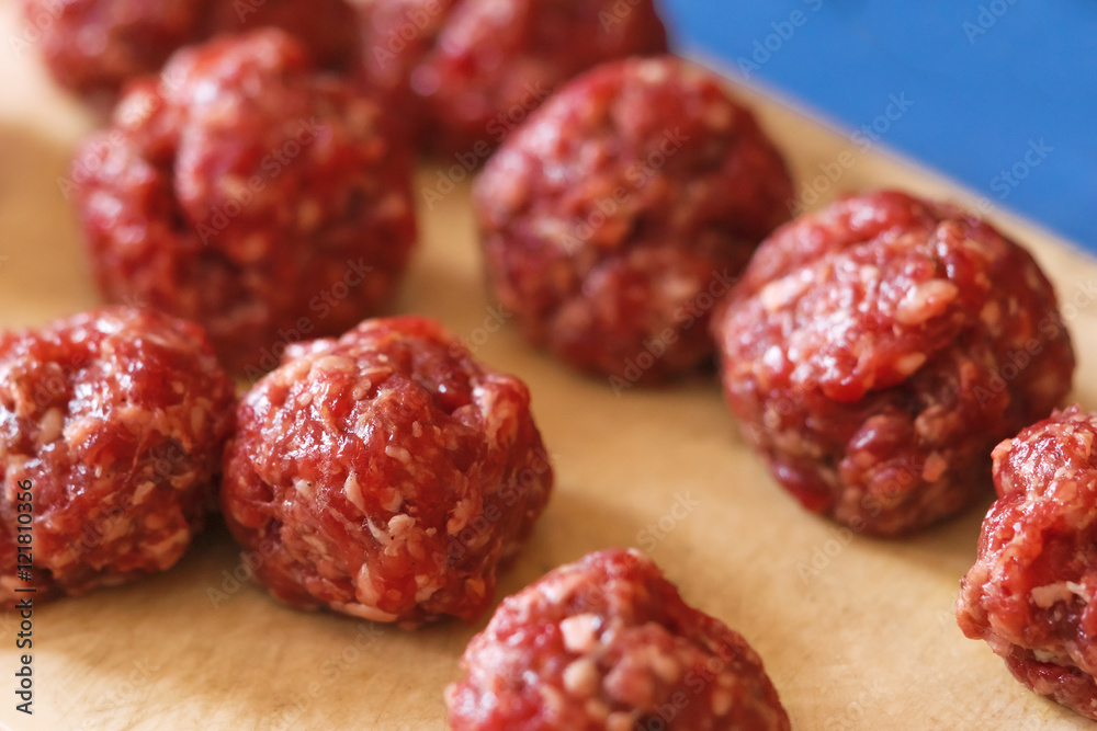 Raw meatballs on a wooden board