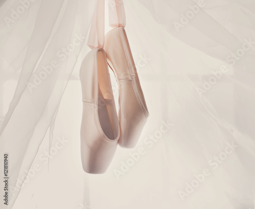 Pink ballet pointe shoes hanging on window