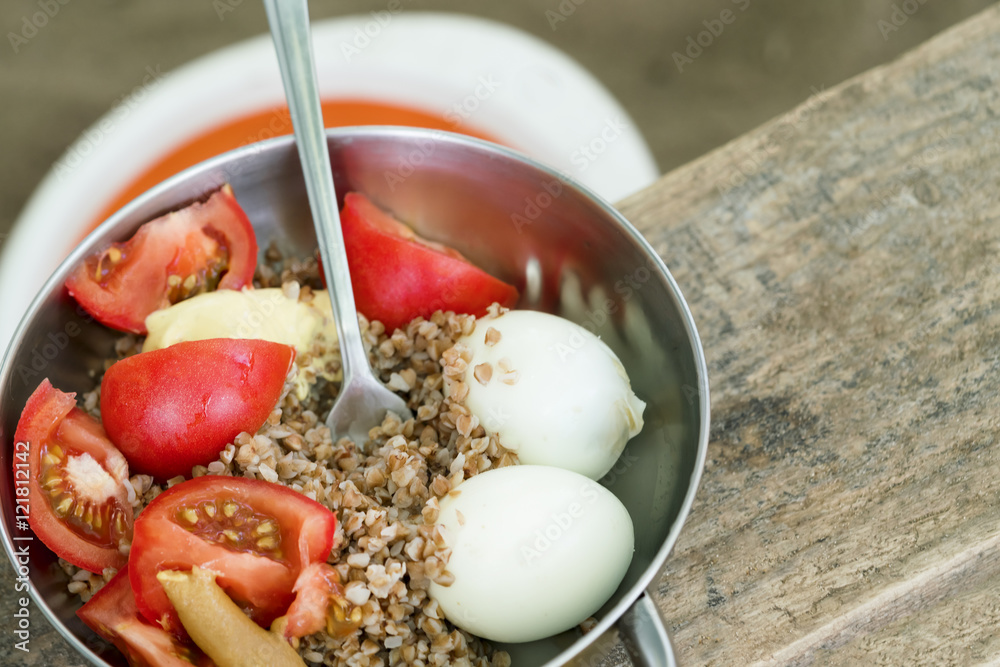 Ταπετσαρία Iron bowl with buckwheat, tomatoes, boiled egg and fork on a wooden table