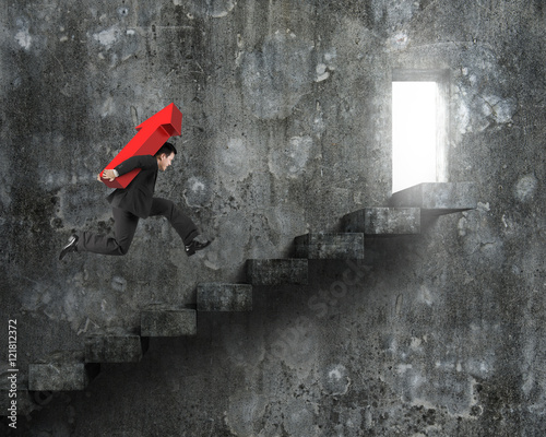 Businessman carrying red arrow sign running on stairs with door