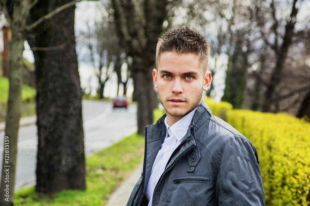 Portrait of handsome young man looking to a side while sitting in city park Portrait of handsome young man looking to a side while sitting in city park