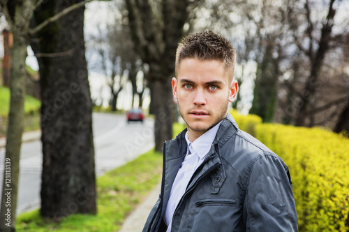 Portrait of handsome young man looking to a side while sitting in city park