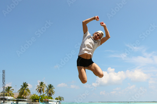 Man jumping happy in the beach with a blue sky in the background © evolutionnow