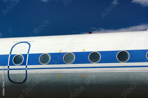 Old passenger aircraft door and windows against blue sky background