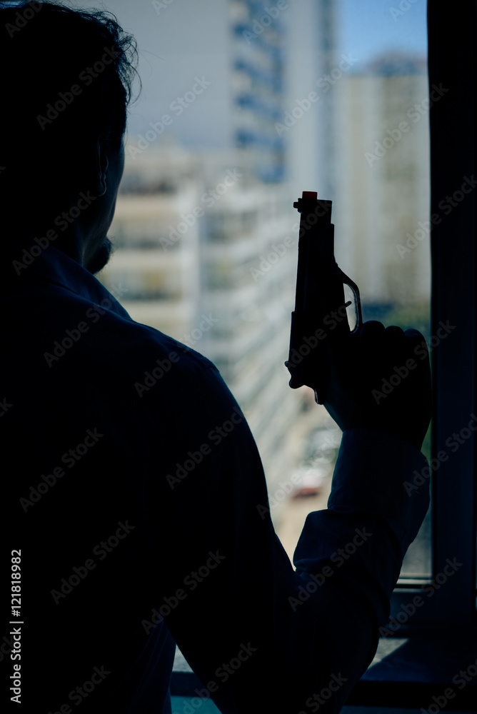Silhouette of a man holding a gun by the window background