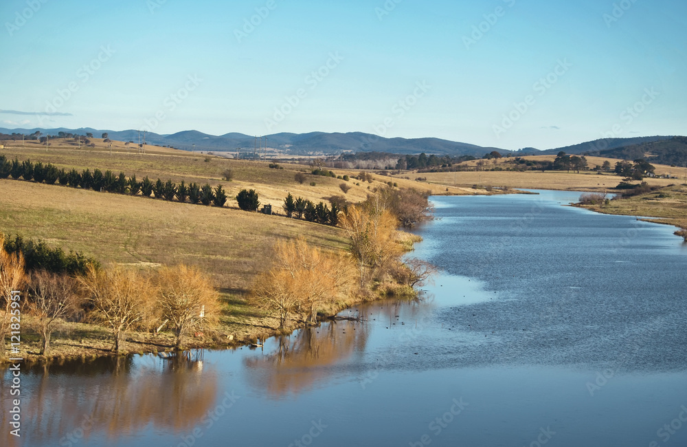 View of river with blue sky and trees during autumn