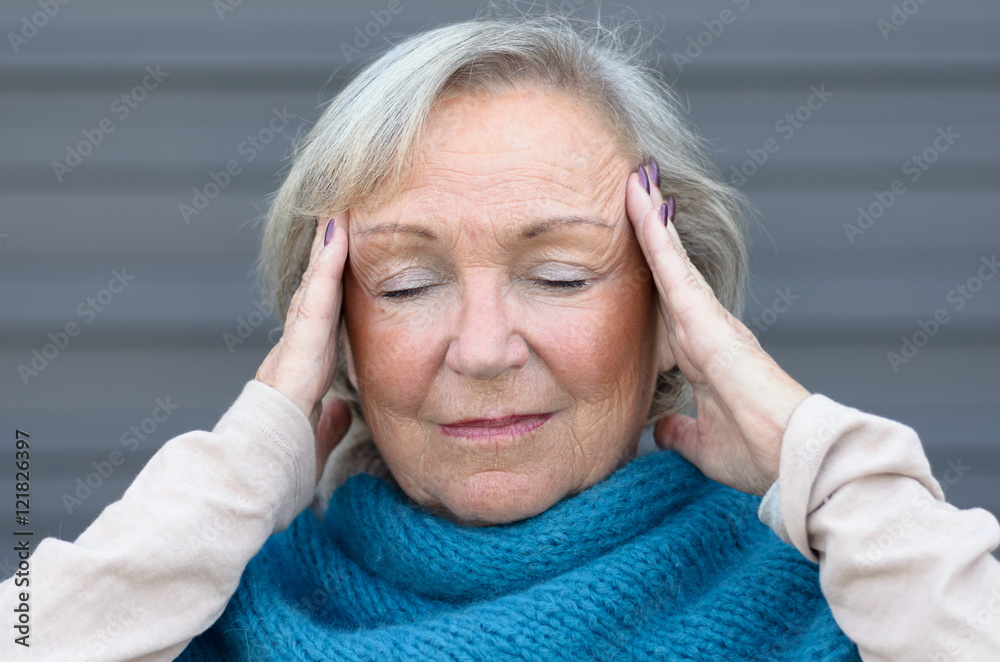 Senior woman holding her hands to her temples Senior woman holding her hands to her temples