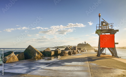 View at Nobbys lighthouse and Nobbys Breakwall during daytime with blue skies and white clouds photo