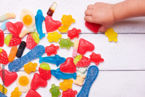 Foto Baby hand takes colorful sweet candies
