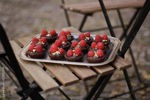Chocolate tartlets with rapsberries on a wooden chair photo