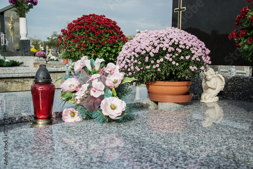 Votive candles lantern and chrysanthemum flowers on tomb stones in graveyard. Graves, tombstones on traditional cemetery. All Saints' Day. All Souls' Day. Gravestones in village Prasice, Slovakia