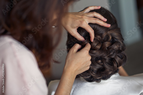 The barber makes hairstyle for bride