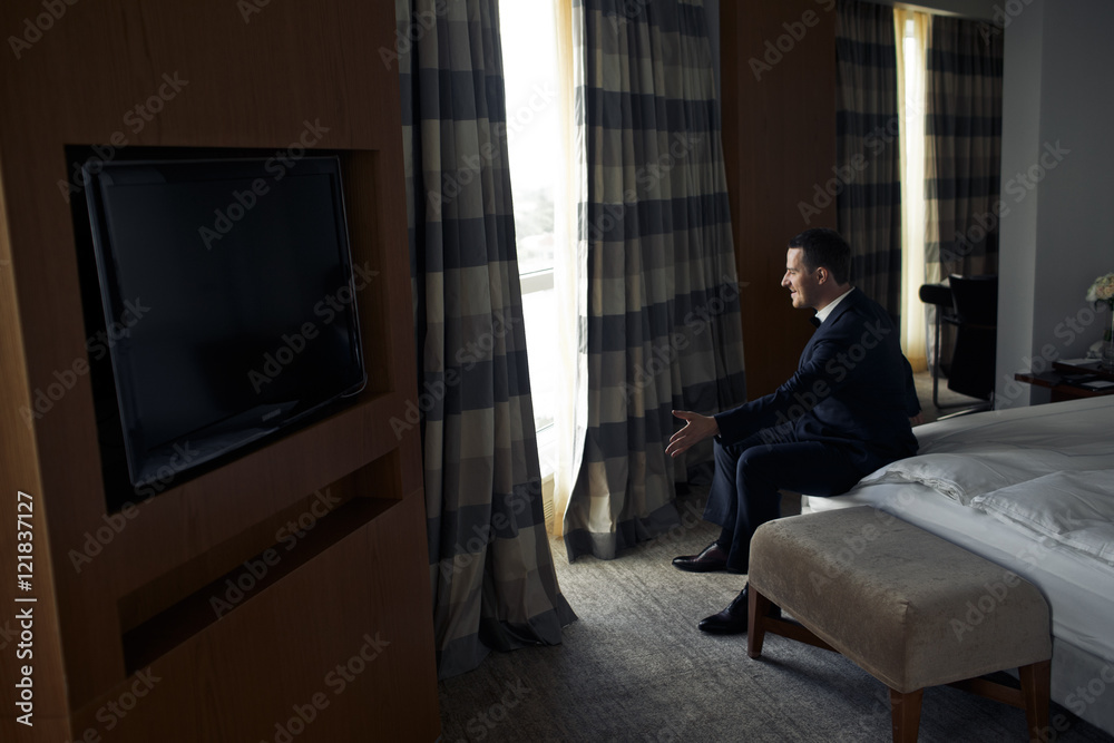 The handsome groom sits near window