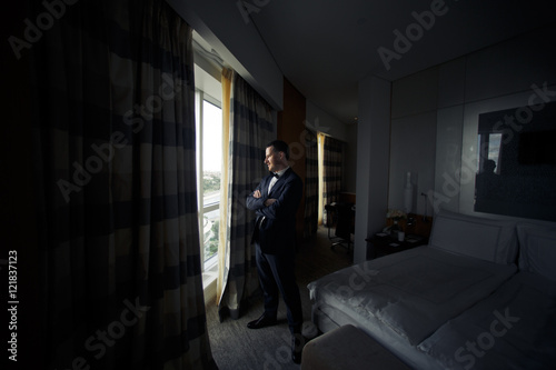 The handsome groom stands near window © nastasenko