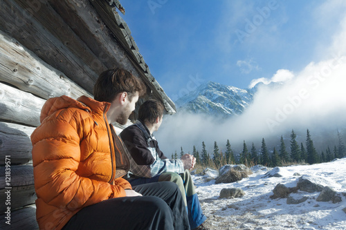 Photography Friends resting on wood bench in winter mountains outdoors