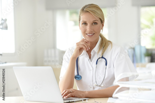 Portrait of doctor in office working on laptop