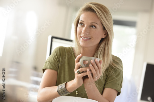 Attractive blond middle-aged woman dinking hot tea