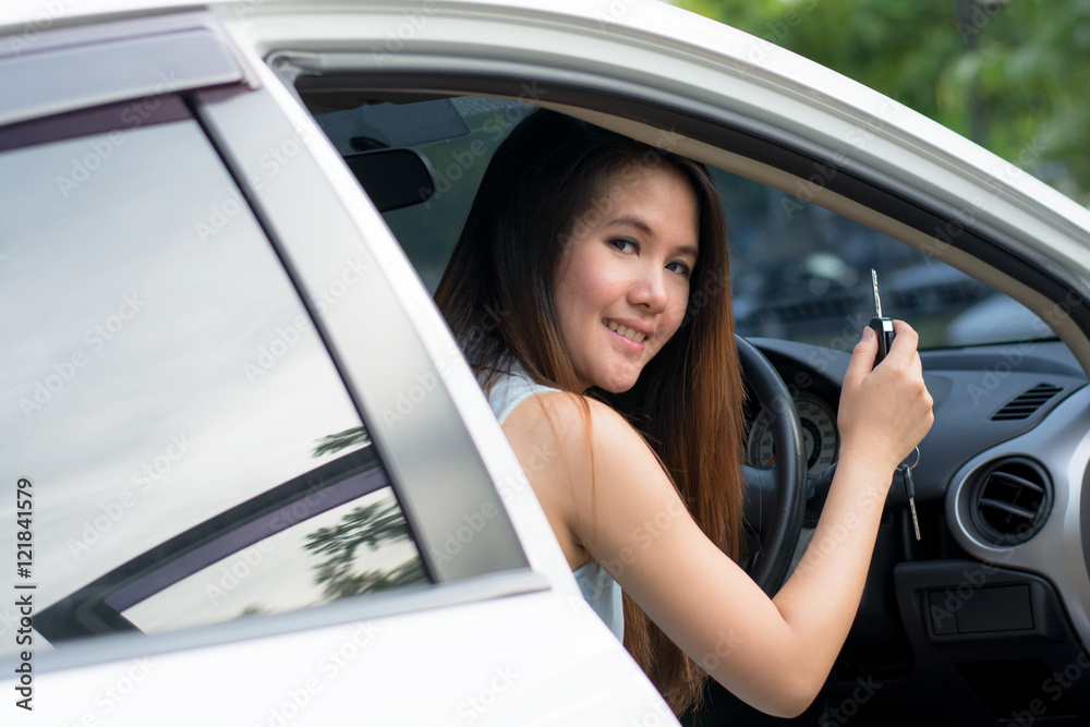 Asian woman smiling showing new car keys and car.