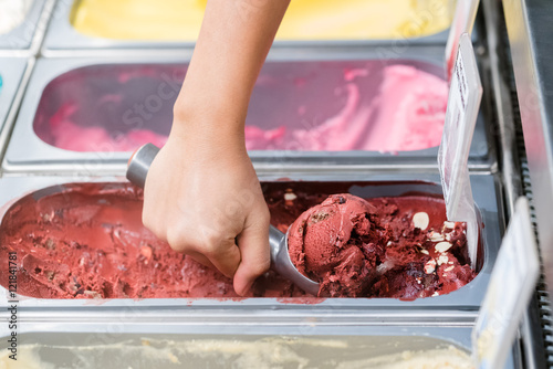 Photo of a metal scoop digging into a tub of ice cream. 