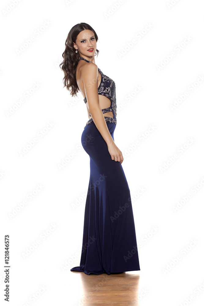 young beautiful woman posing in a long blue dress on a white background