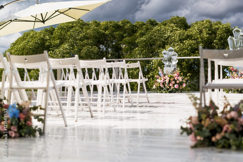 White umbrella hangs over chairs waiting for a wedding ceremony © nastasenko