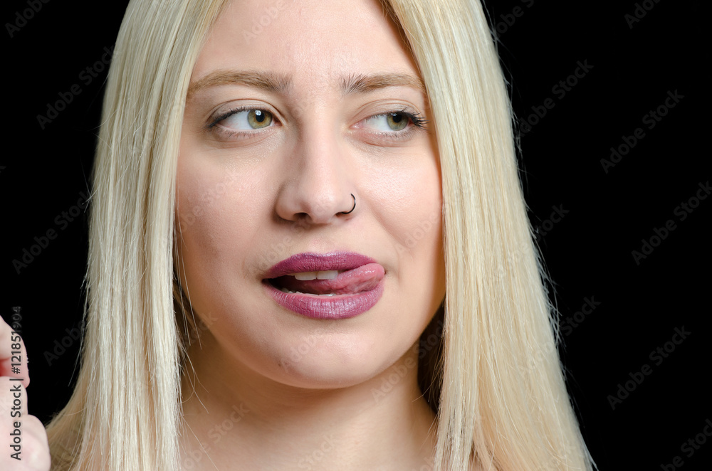 Naklejka premium Woman with green eyes and sexy mouth licks her top lip, black background