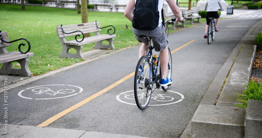 Fototapeta premium Urban biking. Young couple riding bicycle in city park. Healthy summer concept lifestyle