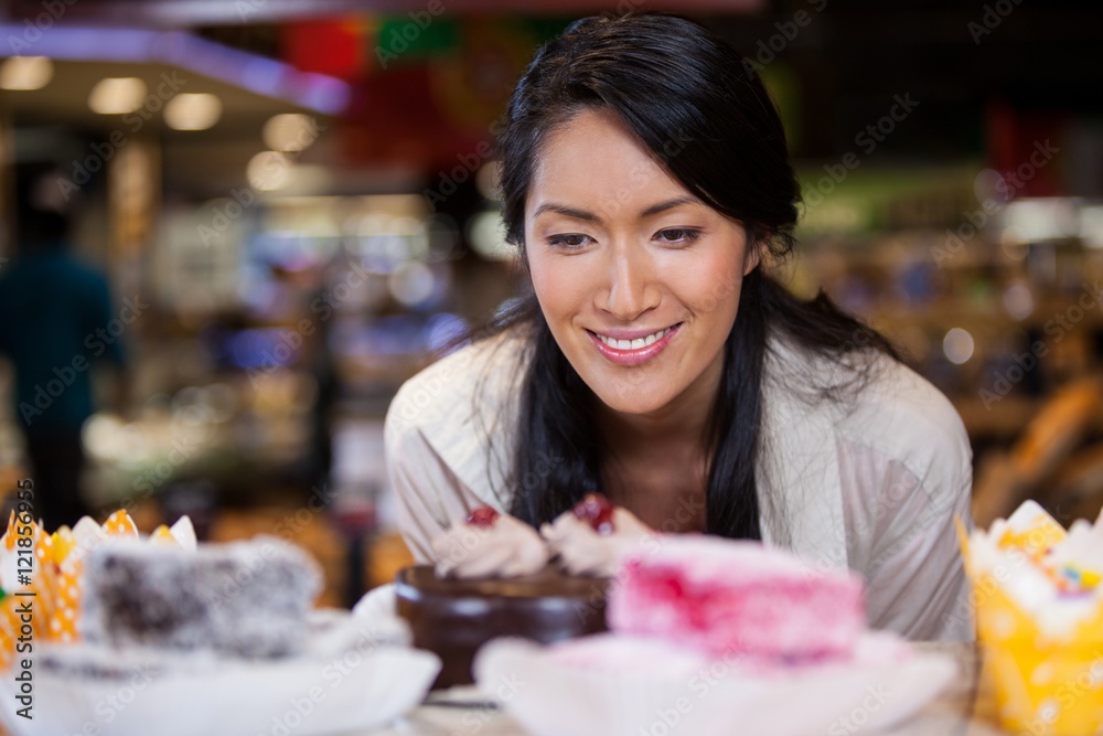 Happy woman selecting desserts from display