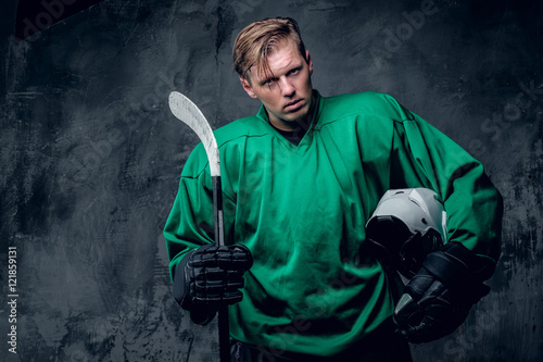Canvas Print Hockey player holds protective helmet and playing stick on grey