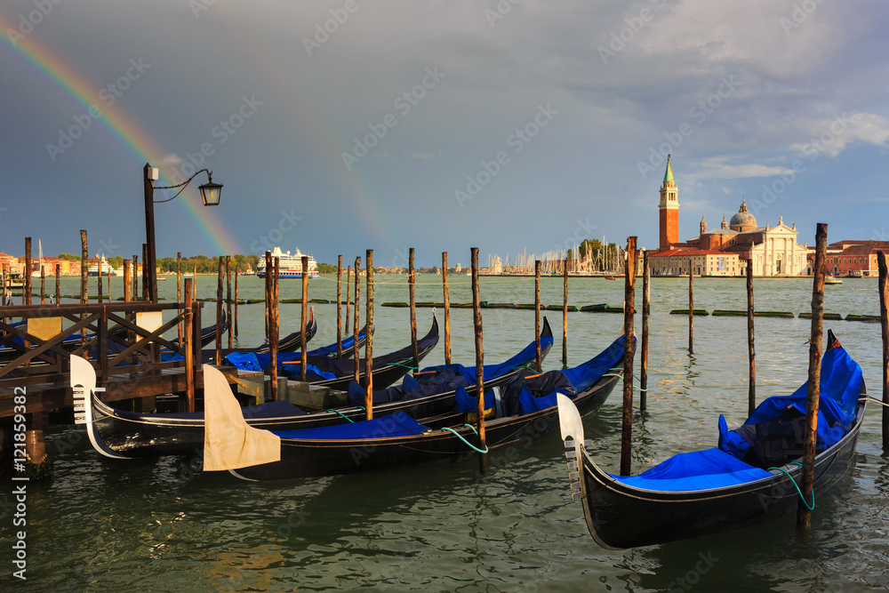 Group of gondola moored in San Marco and across the sea famous San Giorgio Maggiore church.It is spectacular with a nice surprising of rainbow after heavy rain in Venice.