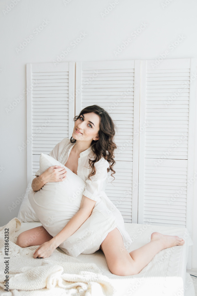 Woman in underwear sitting on the bed hugging a pillow Woman in underwear sitting on the bed hugging a pillow