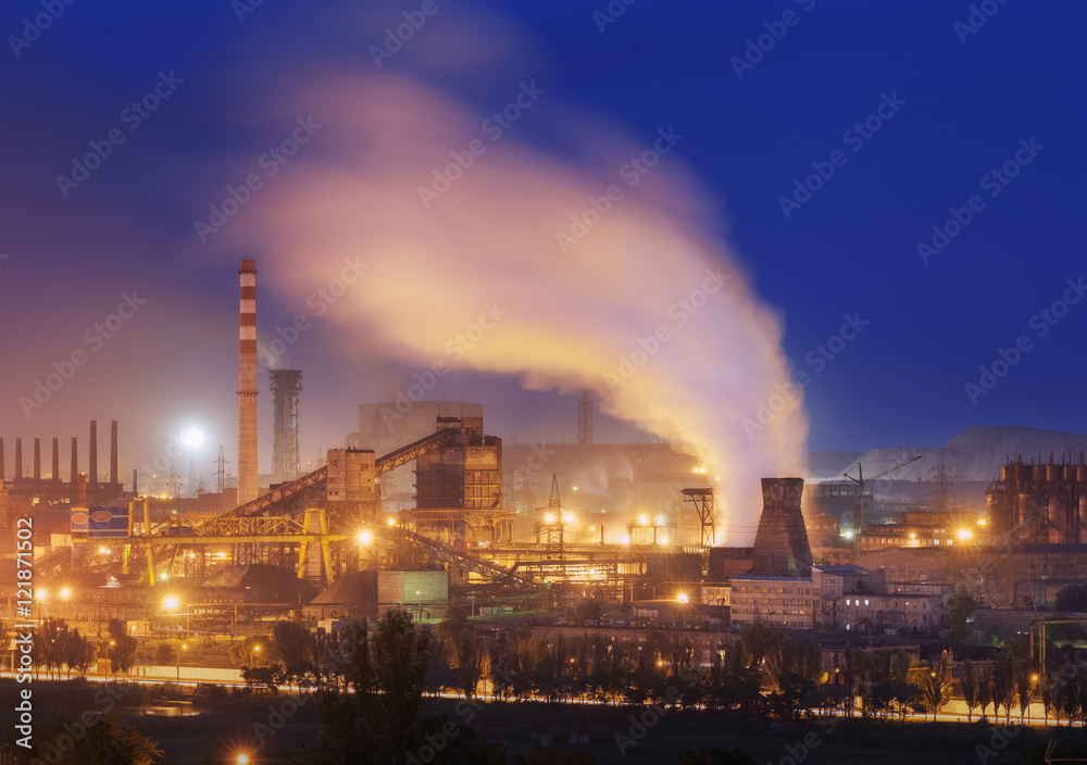 Metallurgical plant at night. Steel factory with smokestacks. Steelworks, iron works. Heavy industry in Europe. Air pollution from smokestacks, ecology problems. Industrial landscape at dusk. Plant