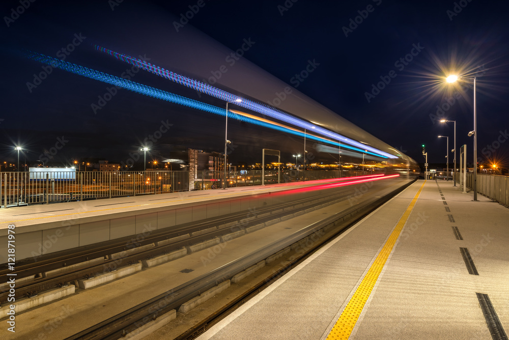 Night view. Train departing from railway station platform with motion blur effect.