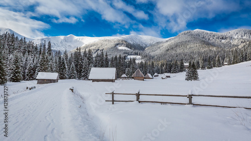 Wooden cottages covered by snow at sunrise in winter, Tatra Mountains, Poland