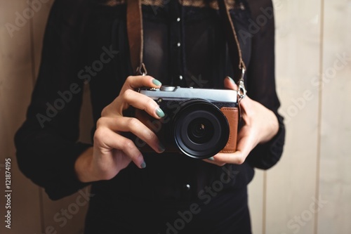 Mid-section of woman standing with camera