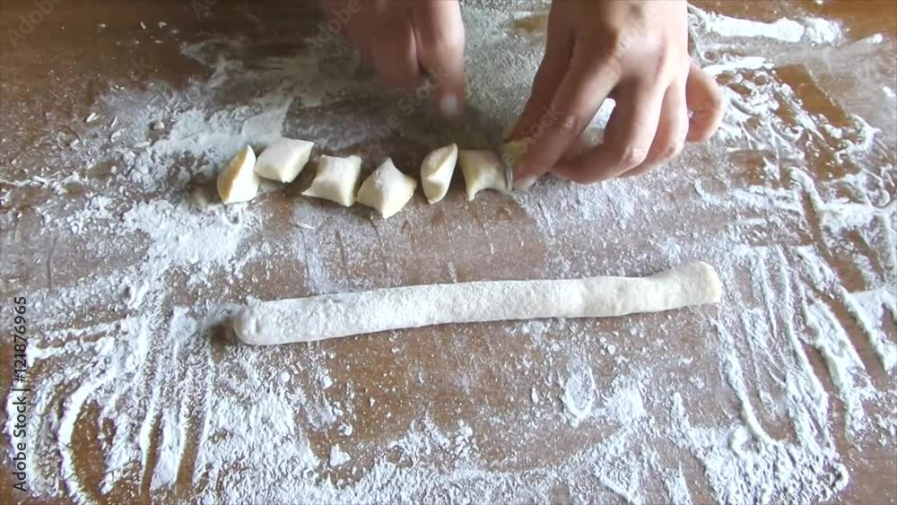 Woman hands making potato gnocchi on wood table with flour.