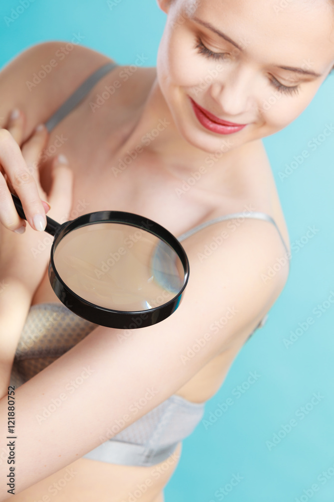 Woman using magnifying glass to examine her moles skin Woman using magnifying glass to examine her moles skin