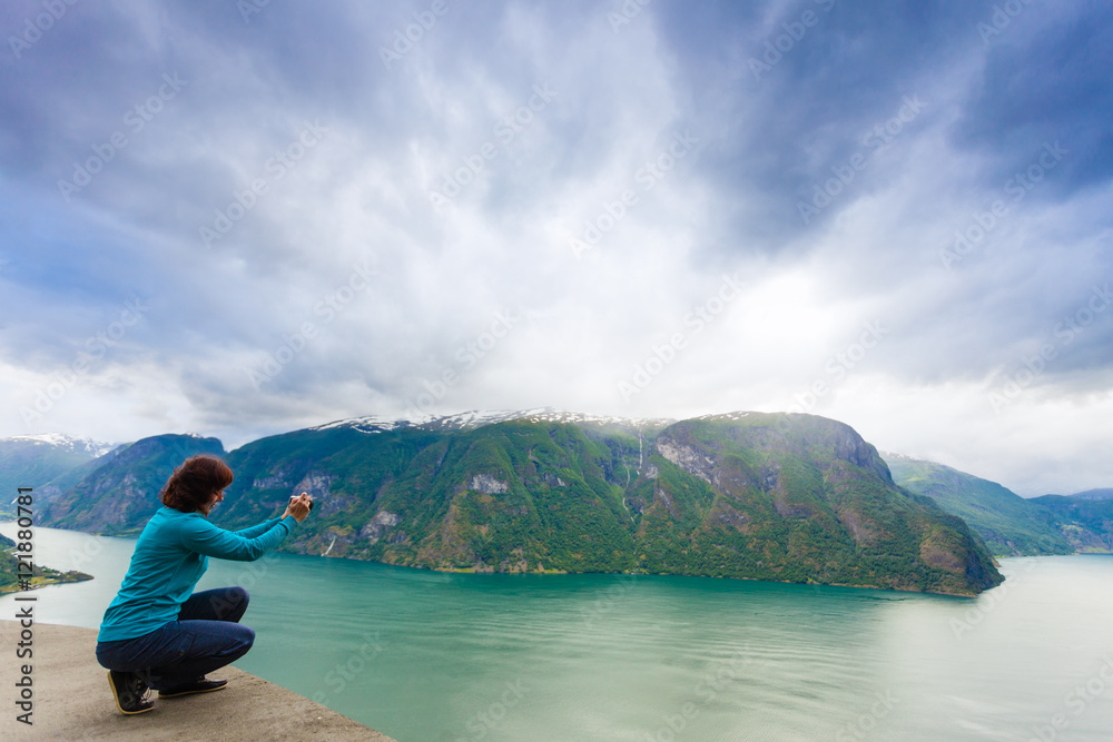 Fototapeta premium Female tourist taking photo at norwegian fjord