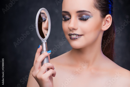 Young woman with small mirror in beauty concept
