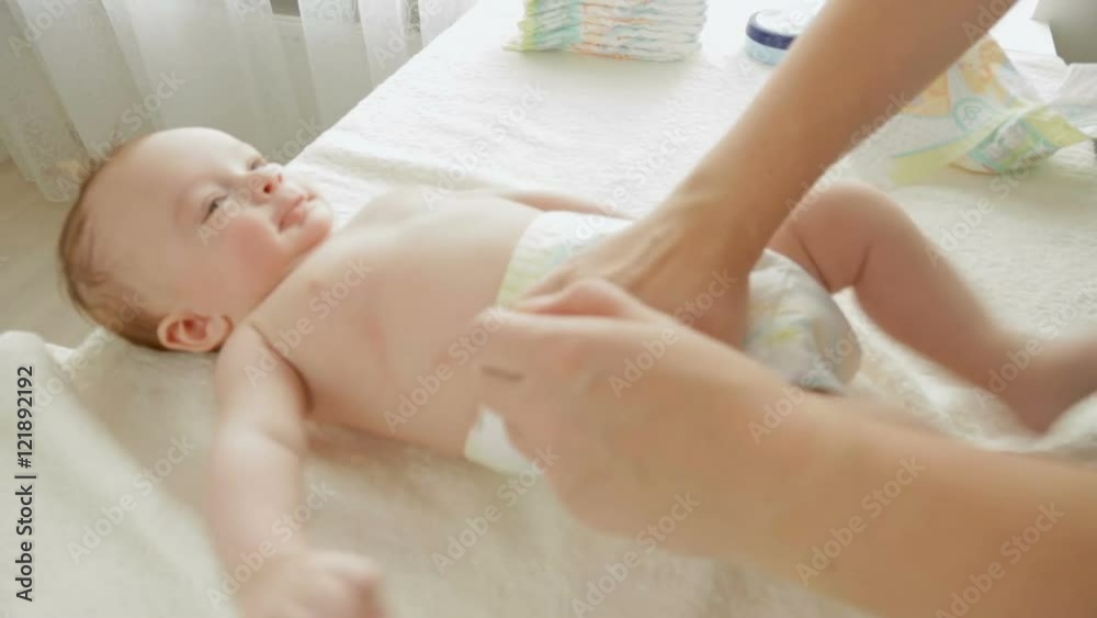Closeup shot of young mother changing diapers to her 3 months old baby boy lying on table Closeup shot of young mother changing diapers to her 3 months old baby boy lying on table