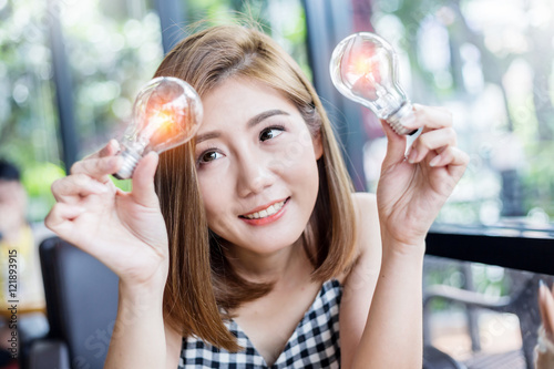 businesswoman holding glowing light bulb in coffee shop