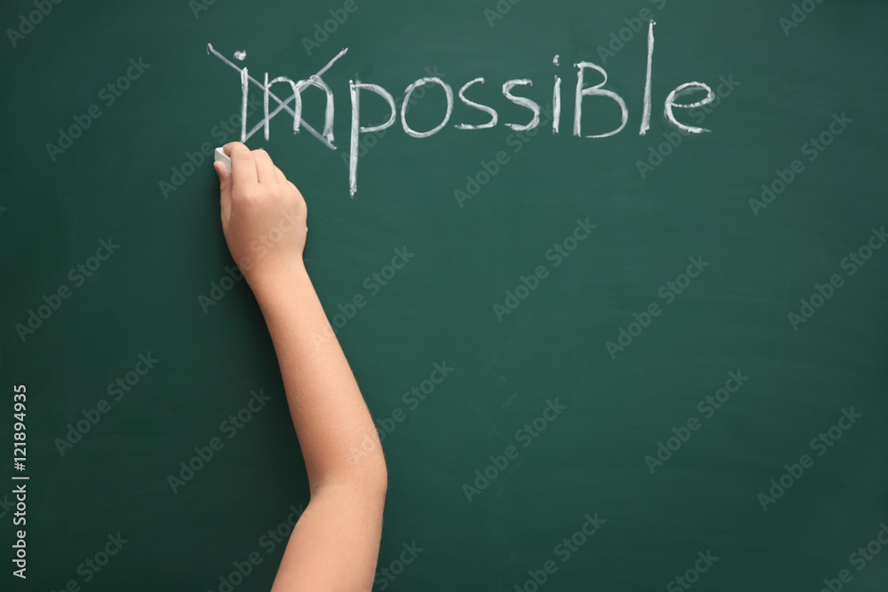 Schoolboy putting a cross over word impossible on blackboard Schoolboy putting a cross over word impossible on blackboard