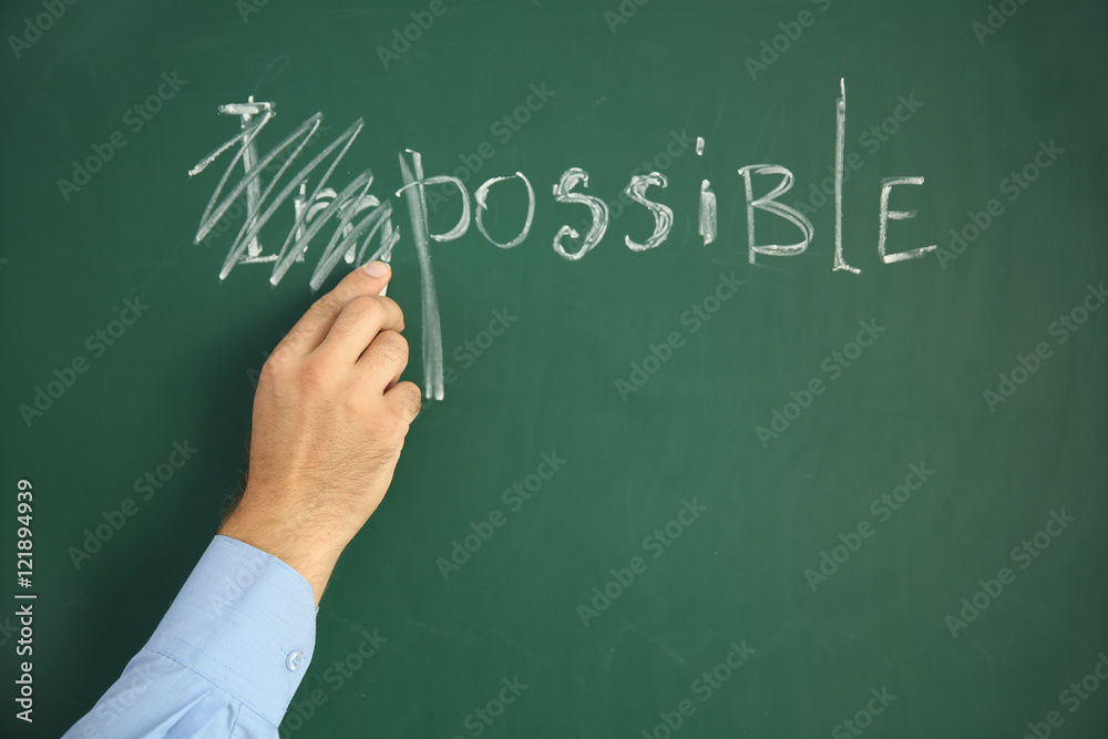 Businessman putting a cross over word impossible on blackboard Businessman putting a cross over word impossible on blackboard
