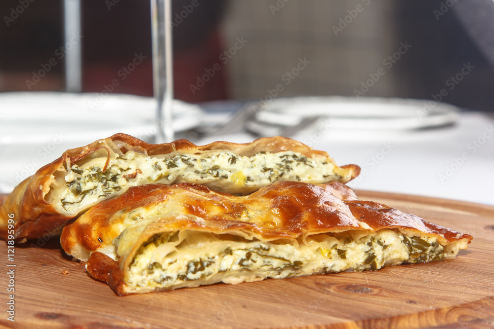 Cake of puff pastry with spinach and cheese on a wooden Board. Cake of puff pastry with spinach and cheese on a wooden Board.