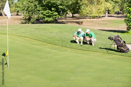 Golfer placing golf ball on the green