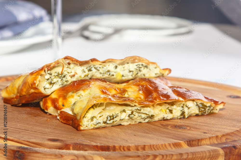 Cake of puff pastry with spinach and cheese on a wooden Board.
