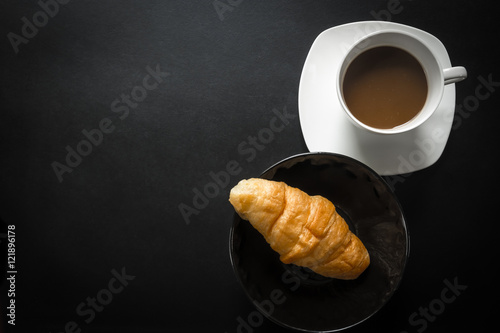 Coffee cup with croissant, Top view. Dark tone.
