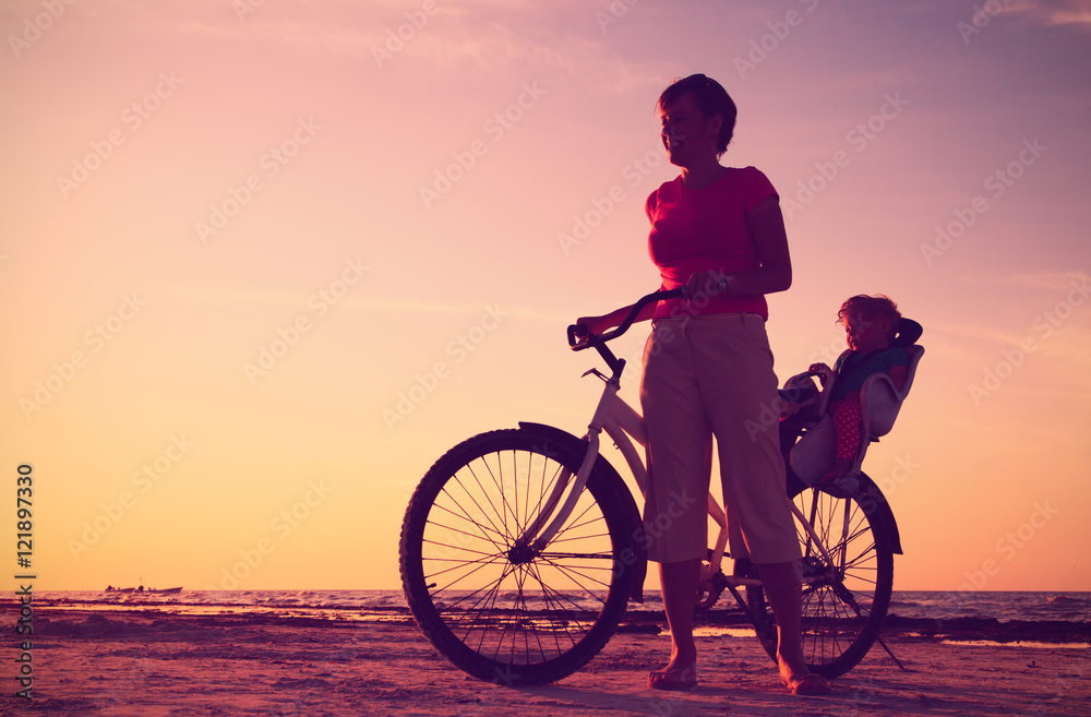 Fototapeta premium Silhouette of mother and baby biking at sunset
