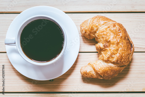 Coffee and croissant for breakfast on wooden table
